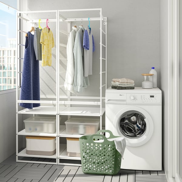 Well-organized laundry room. Washers and shelves filled with clothes and storage bins. A green mesh laundry basket sits on the floor, ready for use.
