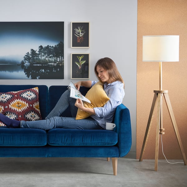 Person reading on blue SMEDSTORP sofa in cosy living room.