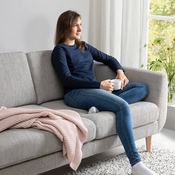 Person on SMEDSTORP sofa with cup. Comfortable, retro design with resilient foam.