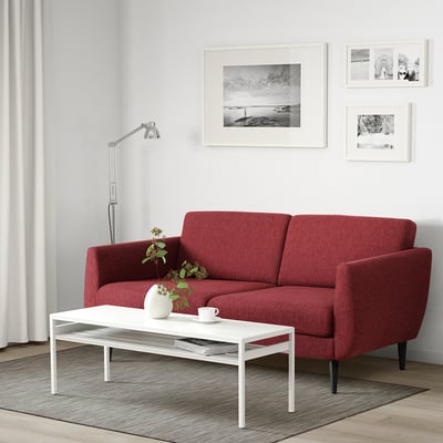 Red sofa, black-white art, plants, minimalist room.