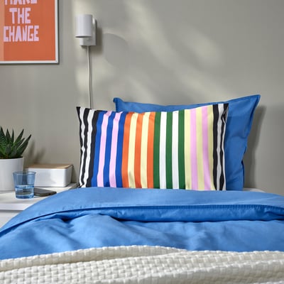 SNÖDROTTNING striped pillowcase on blue duvet, larger than glass, white background.