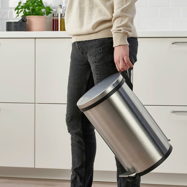 Person holding a stainless steel pedal bin with a handle, suitable for waste or recycling, easy to move and clean.