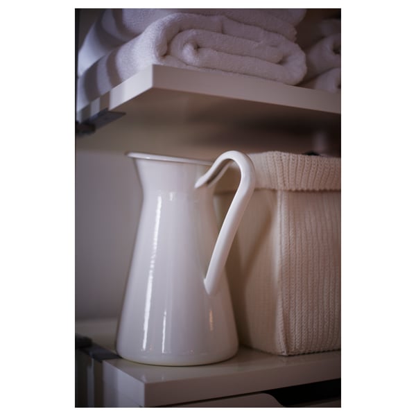 White enamel jug on shelf with towels, simple and clean design.