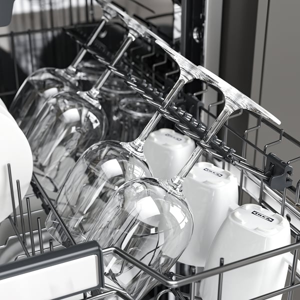 Open dishwasher with upper basket holding glasses and white containers, showing adjustable racks.