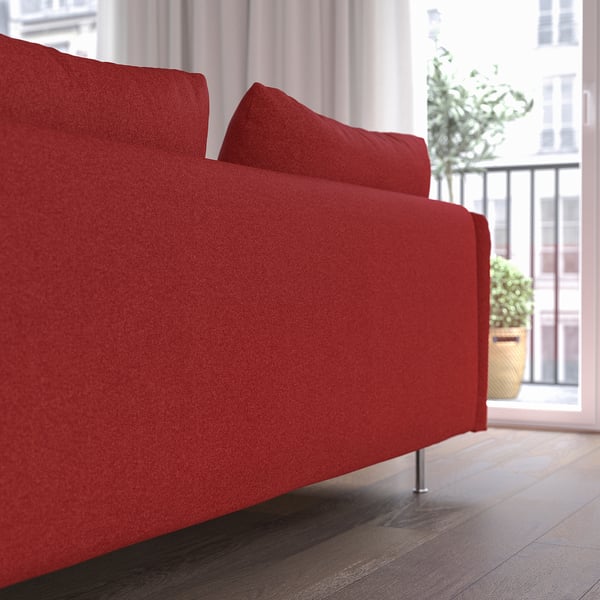 Red sofa near window with plants, offering comfort and style.