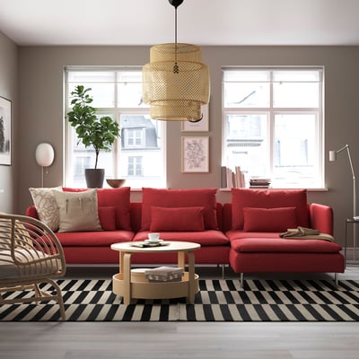 Red SÖDERHAMN sofa in cosy living room with large window, plush cushions, wooden floors, black/white rug, rustic coffee table, and pendant light.