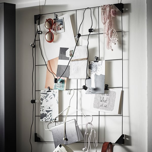 A SÖSDALA memo board, black, with metal clips holding papers and photos. A necklace hangs from it.