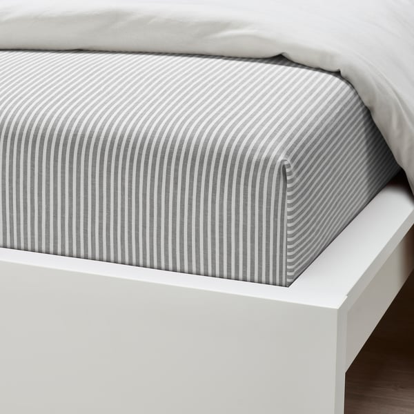 Striped cotton mattress cover on a white bed frame. Modern, minimalist, high-quality look.