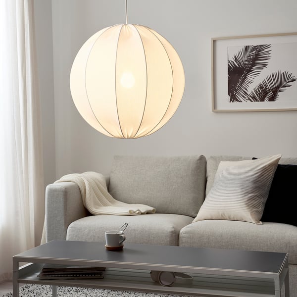 Hanging lamp illuminates cosy living room with grey sofa and accessories.
