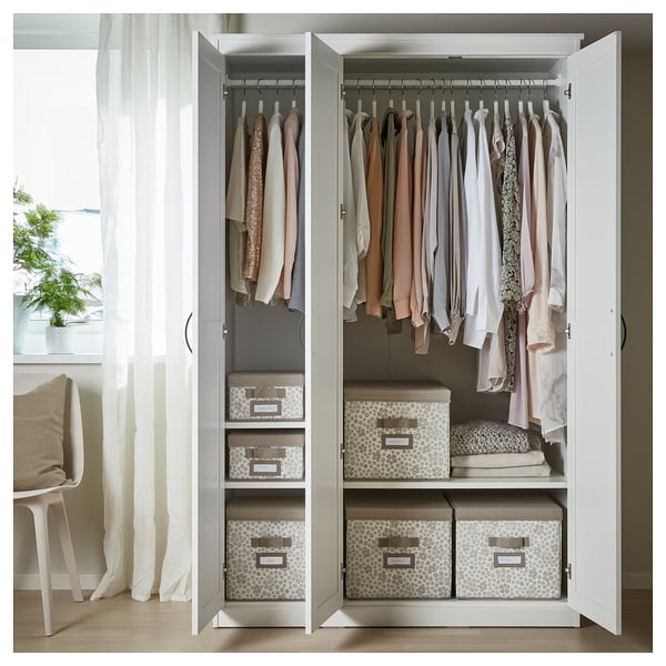 A white SONGESAND wardrobe with mirrored doors, neatly organised clothes, and storage boxes.
