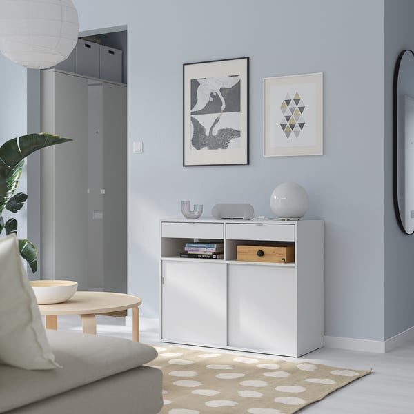 Modern minimalist living room with white SPIKSMED sideboard, versatile storage, grey wall, art, mirror, and sofa.