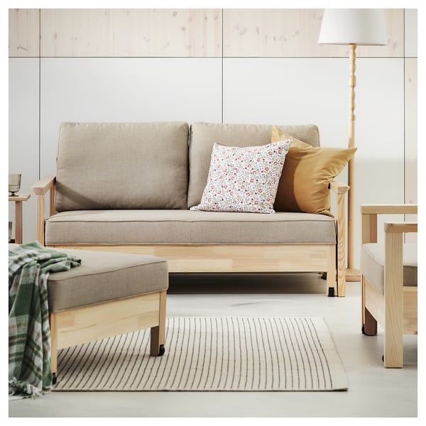 Minimalist living room with grey sofa, wooden textiles, striped beige rug, and standing lamp.