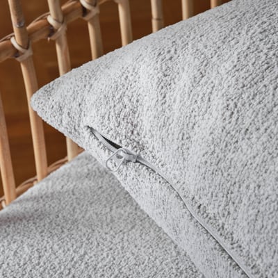 Close-up of armchair zip on white, textured fabric.