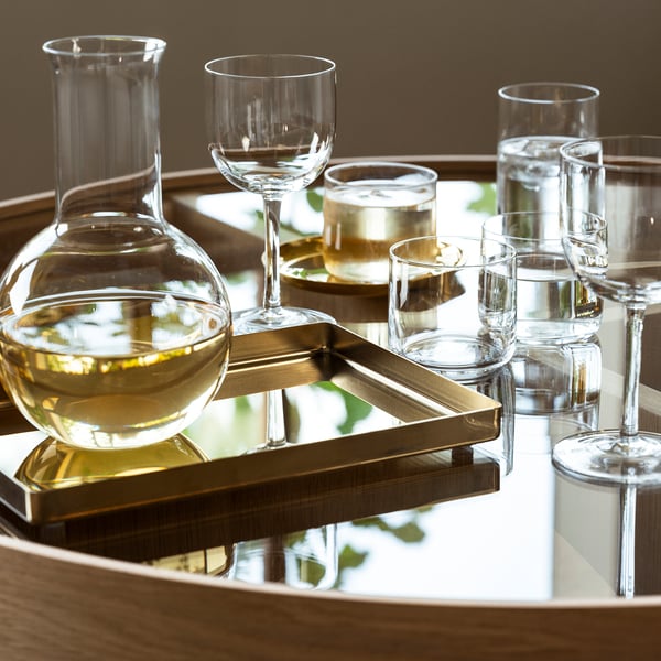 A glass carafe and multiple wine glasses on a tray, ideal for serving wine or water, part of the STOCKHOLM 2025 collection.