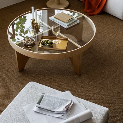 STOCKHOLM 2025 coffee table with glass top & oak accents, holding wine glass, candles, books, snacks. Modern scandinavian design.