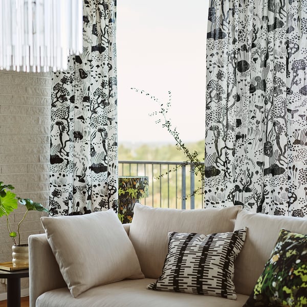 Modern living room with stockholm curtain and beige couch, striped pillows, and patio view.