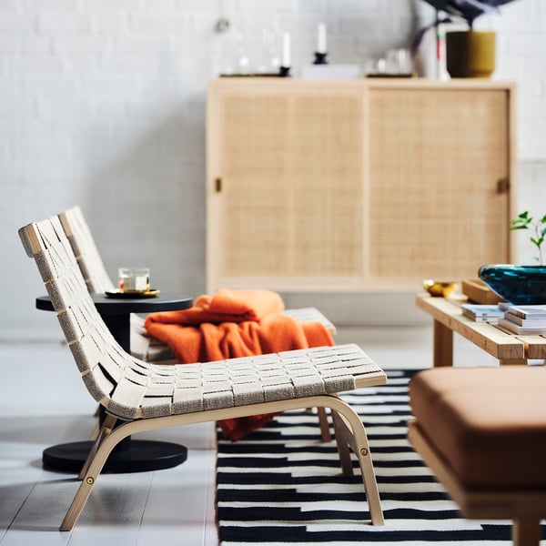 STOCKHOLM 2025 easy chair in modern living room. Light wood, linen bands, minimalist design.