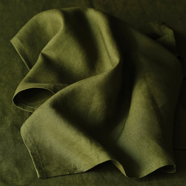 Folded green linen napkin, showcasing its smooth texture and natural beauty, perfect for elegant table settings.