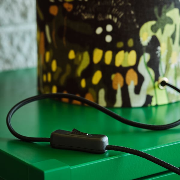 Black corded table lamp with a green base and intricate, colourful pattern, featuring a switch for controlling the light.