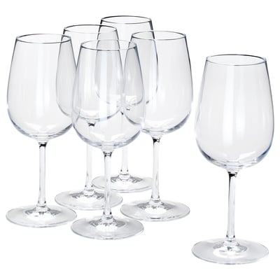 Six clear crystalline wine glasses arranged neatly, five upright and one on its side, showcasing their stems and bases.