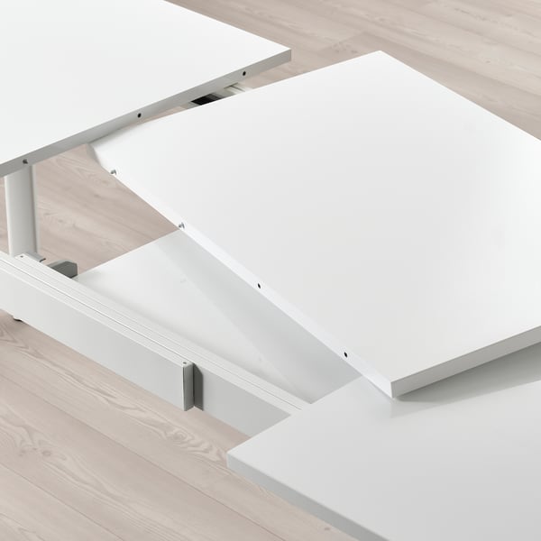 White extendable dining table, STRANDTORP, with 2 self-storing leaves, shown partially extended.