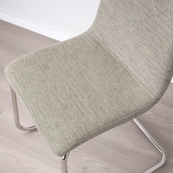 Chair with light grey textured fabric, sleek metal frame, on wooden floor.