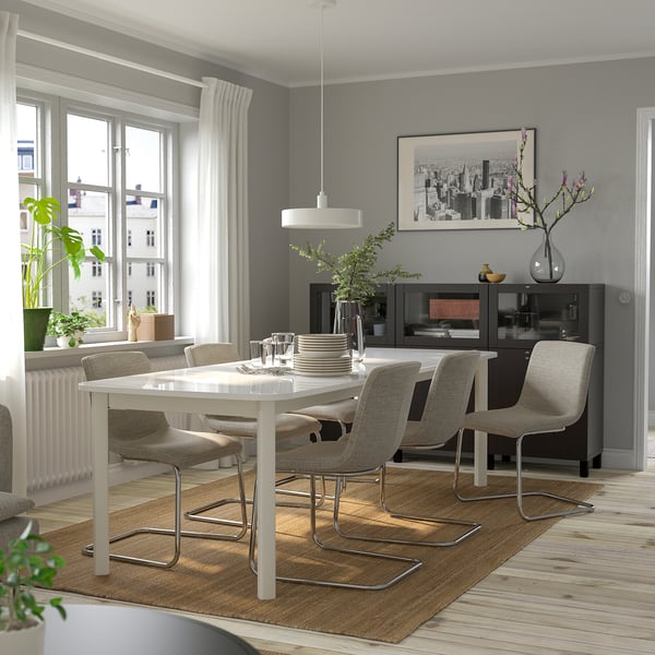 Contemporary dining room with STRANDTORP table, beige chairs, and cityscape decor.