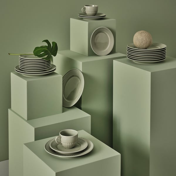 Green STRIMMIG porcelain set with circular plates and cups, plant included. Modern, detailed design.