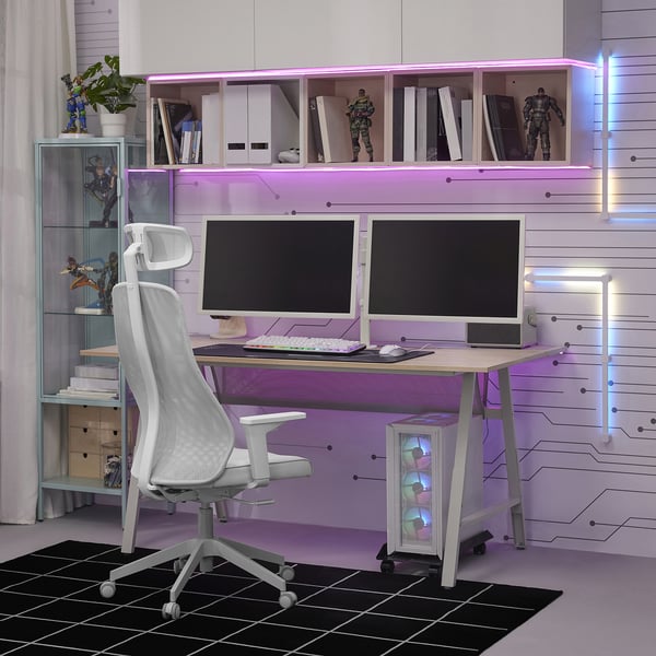 Modern gaming setup: dual screens, white chair, purple led lights. STUBBERGET mount for clear desk with action figures, books, plants on shelves.