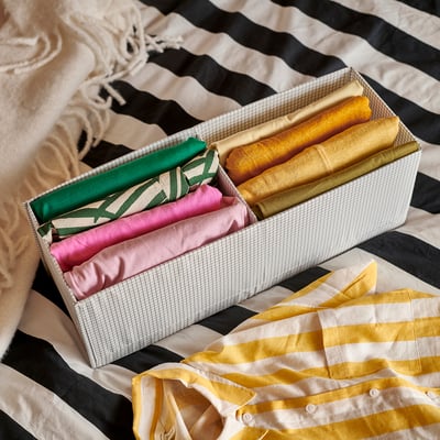 Organised storage box with rolled fabrics. Stripes and solid colours visible.