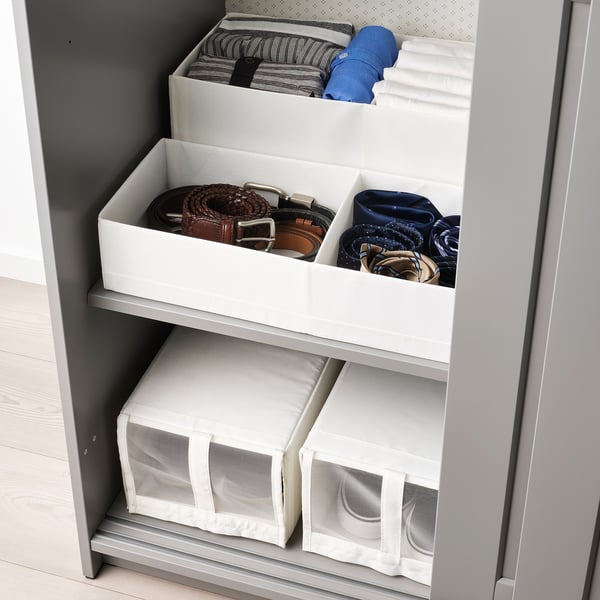 Closet organiser with white boxes storing belts and folded clothes neatly on shelves. Labels visible for easy access.