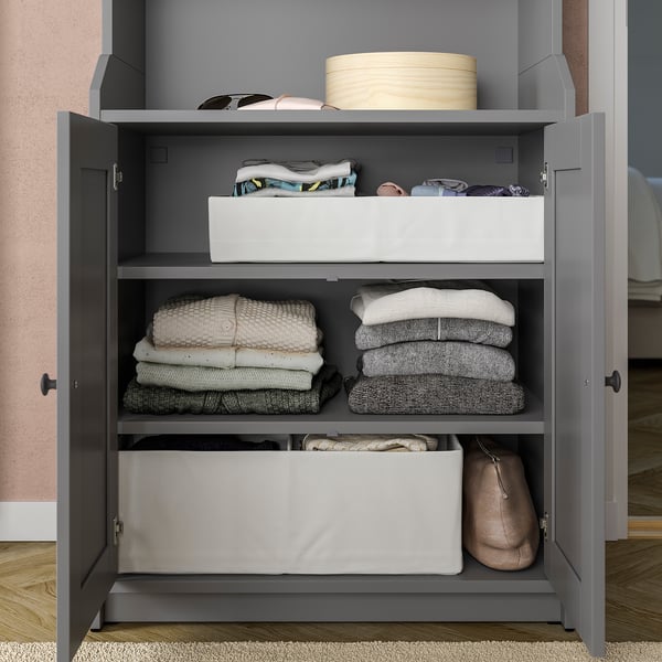 Open grey closet with folded clothes and boxes on shelves.