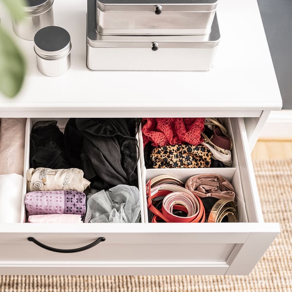 Open drawer with organised socks in compartments. Include black, red, patterned, and neutral socks in a white drawer.