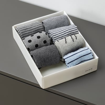 Box of folded socks with varied patterns neatly organised.