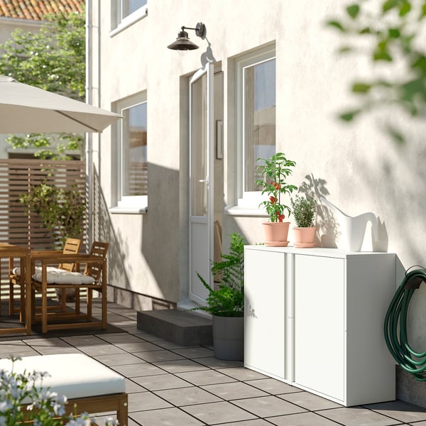 Modern outdoor cabinet, white, metal, rectangular, with two potted plants.