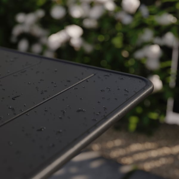 Black outdoor table with water droplets, set outdoors, part of the SUNDSÖ series.