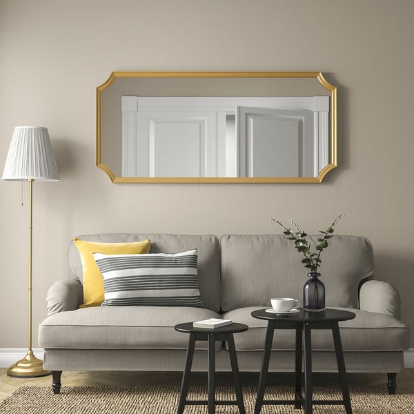 Gold-framed SVANSELE mirror above grey sofa, adds luxury.