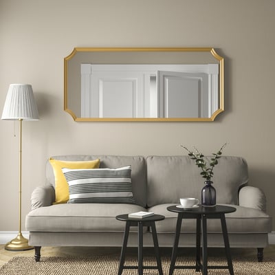 Gold-framed SVANSELE mirror above grey sofa, adds luxury.