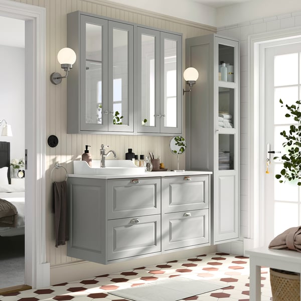 Grey TÄNNFORSEN vanity with sink, drawers, mirrored cabinets, bevelled panels, wall sconces, geometric-tiled floor.