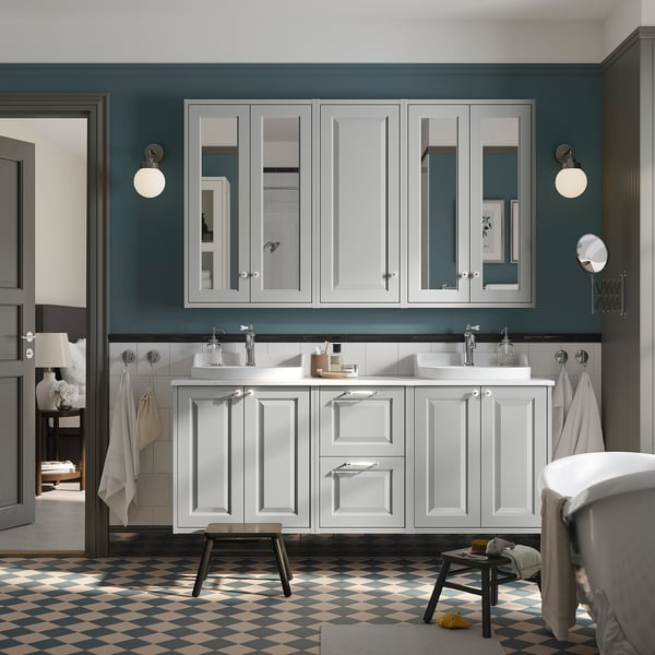 Modern bathroom with large TÄNNFORSEN white vanity, double sinks, grey walls. Chequered floor, round mirrors.