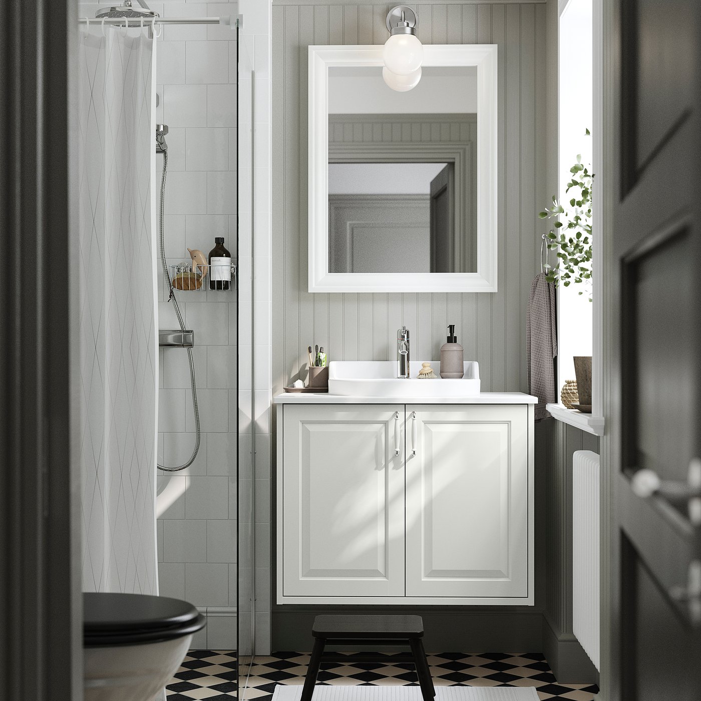 A white TÄNNFORSEN bathroom cabinet, narrow, with a sink, mirror, and black & white floor.