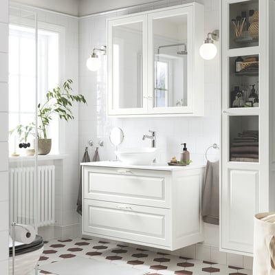 Modern white bathroom vanity with bevelled edges, sink, and mirror. Elegant design, large, well-lit.