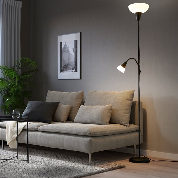 Living room with TÅGARP lamp, beige sofa, cushions, side table with blanket & plant, framed photo.