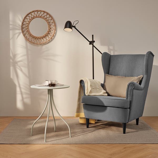 Modern living space with chair, side table, lamp, and mirror. Cosy wooden floor setup.