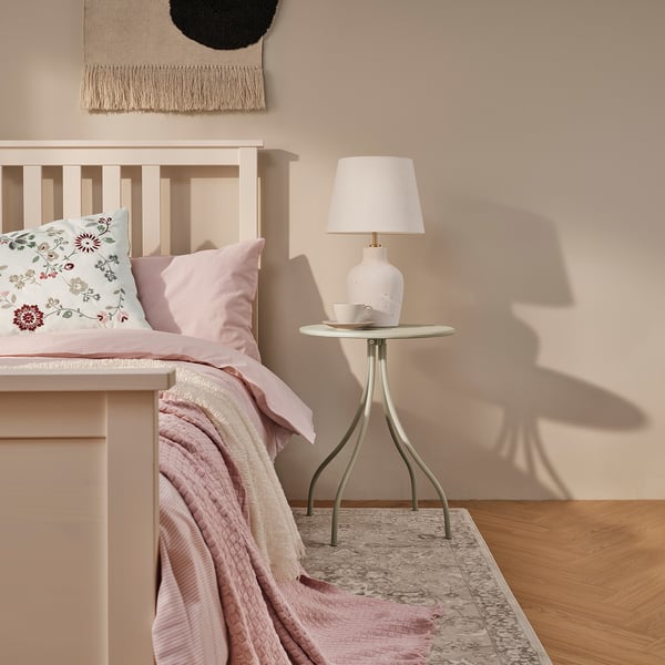 Beige TÅNEBRO bedside table with lamp.
