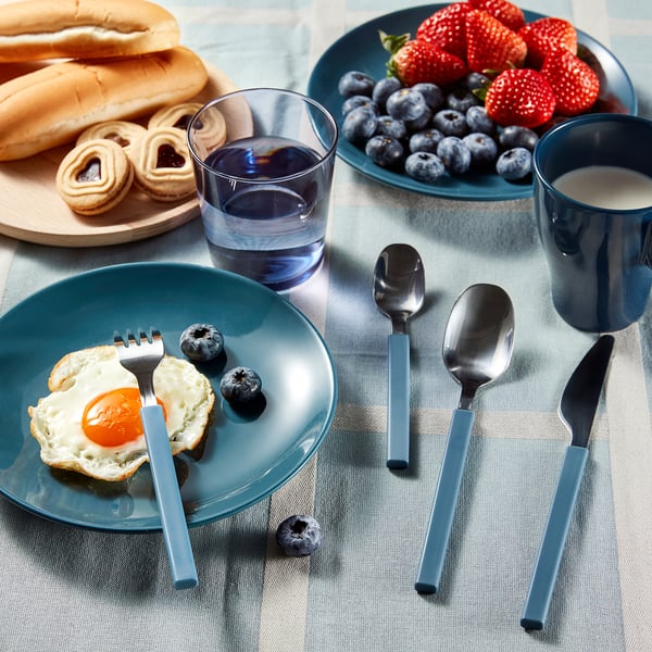 Breakfast table: bagel, berries, juice, fork, knife, spoon, blue plates.