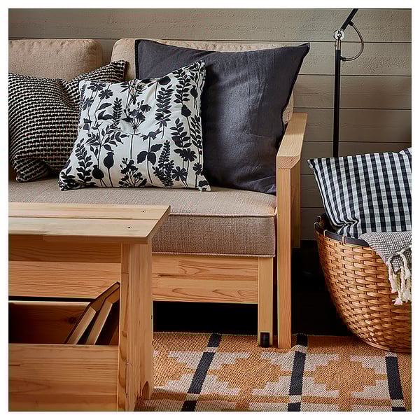 A cosy seating area with a wooden bench, cushions, and a woven basket. The cushions feature patterns in black, white, and neutral tones.