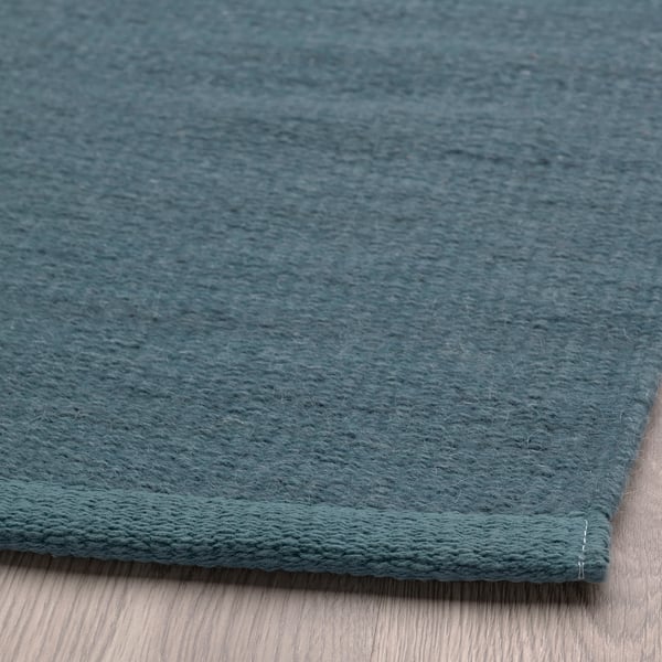 Blue-gray wool rug, flatwoven, soft texture, lays on wooden floor.
