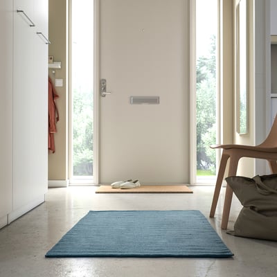 Modern entryway with TIDTABELL rug, grey-blue, adding warmth and comfort.