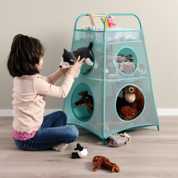 A girl organises toys into a mesh storage unit with circular openings, promoting tidy play and easy access.